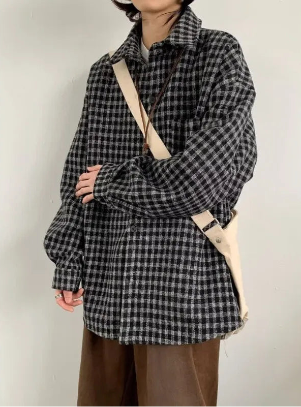 Person wearing a black and white checkered shirt with a beige strap over a plain background