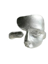 Silver ring with a face design on a gray background