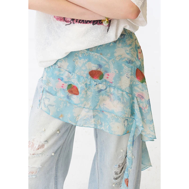 A light blue ruffled wrap skirt with a strawberry and cloud pattern, worn by a model with distressed light-wash jeans and a white top.