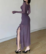 Woman wearing a long purple dress with a high slit, standing against a plain background.