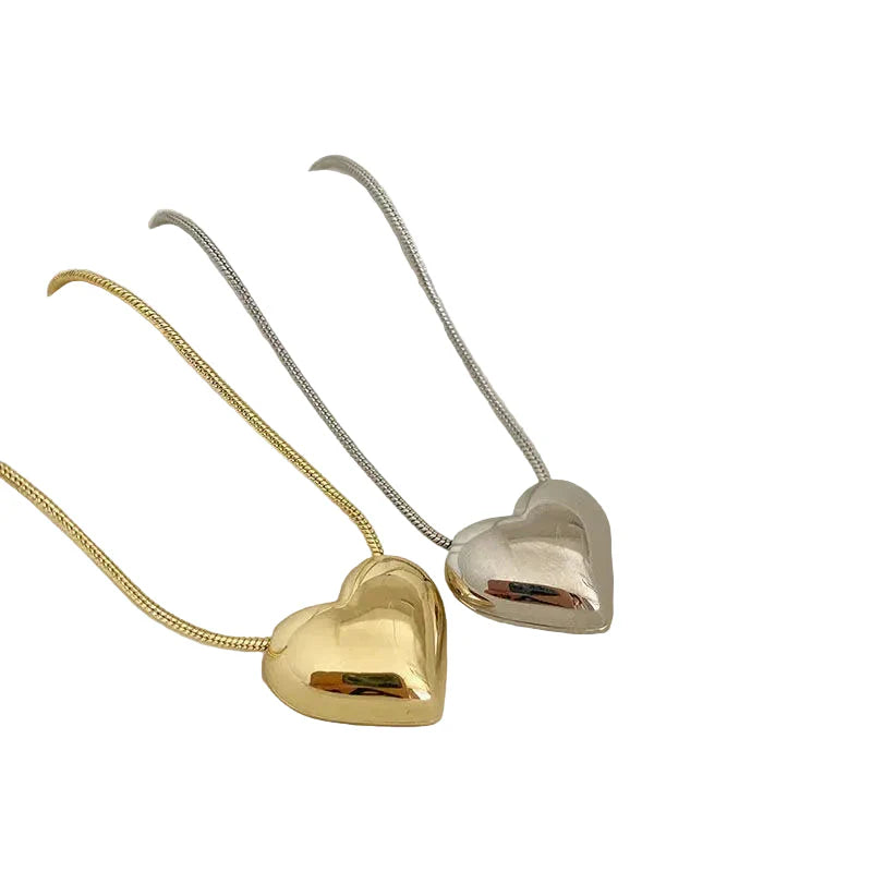 Gold and silver heart-shaped pendants on necklaces against a white background