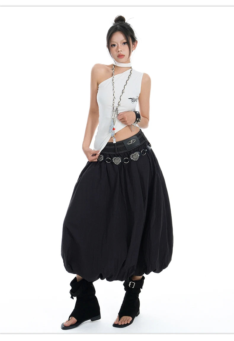 A model wearing a gothic punk style outfit consisting of a white halter crop top with silver chain details, a black harem-style skirt with a silver ring belt, and black ankle boots, set against a plain white background.