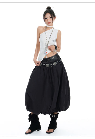 A model wearing a gothic punk style outfit consisting of a white halter crop top with silver chain details, a black harem-style skirt with a silver ring belt, and black ankle boots, set against a plain white background.