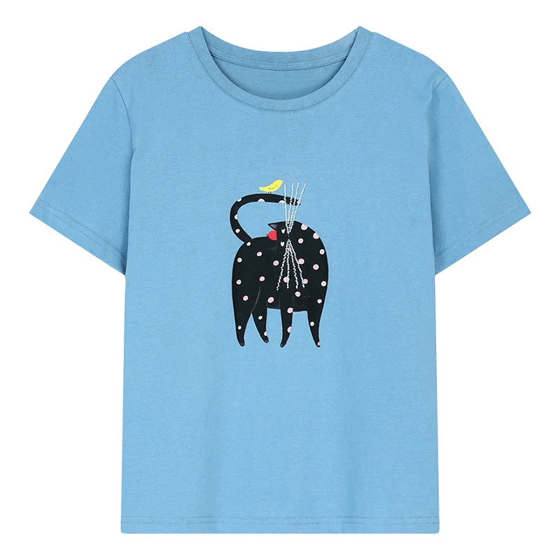 A light blue short-sleeve crewneck t-shirt featuring a graphic print of a black elephant with white polka dots, holding a bundle of sticks, with a small yellow bird on its back.