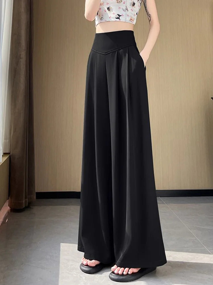 Person wearing black wide-leg pants in a minimal indoor setting