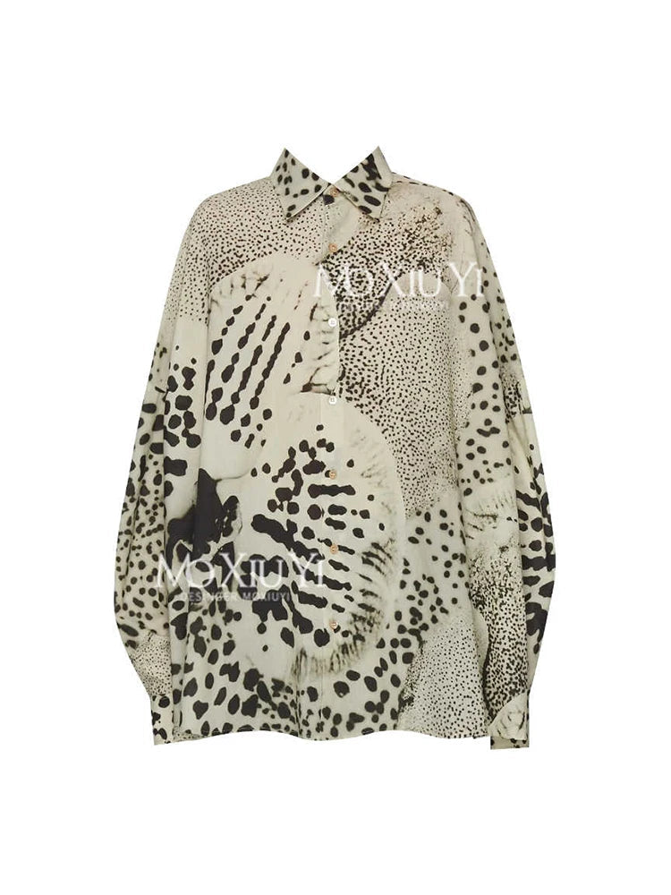 A long-sleeve button-up shirt by Qunzy Studio featuring an abstract animal print pattern in black, beige, and cream. The shirt has a pointed collar and is displayed against a plain white background with brand text at the top and watermark text across the center.