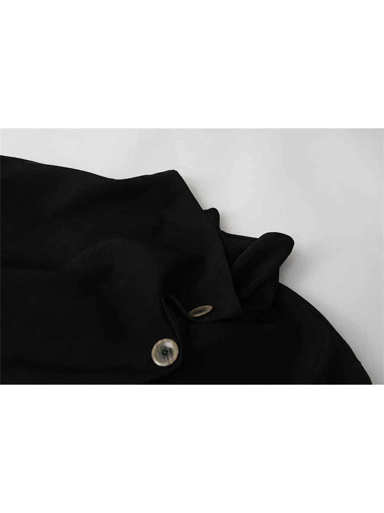 Close-up of a black garment with a buttoned collar detail on a light gray background.