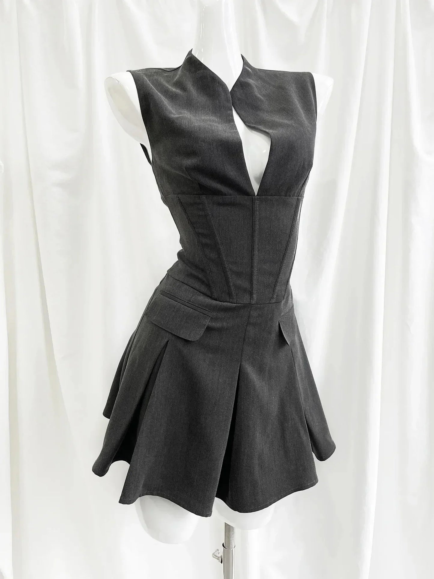 Black sleeveless dress on a mannequin against a white curtain background