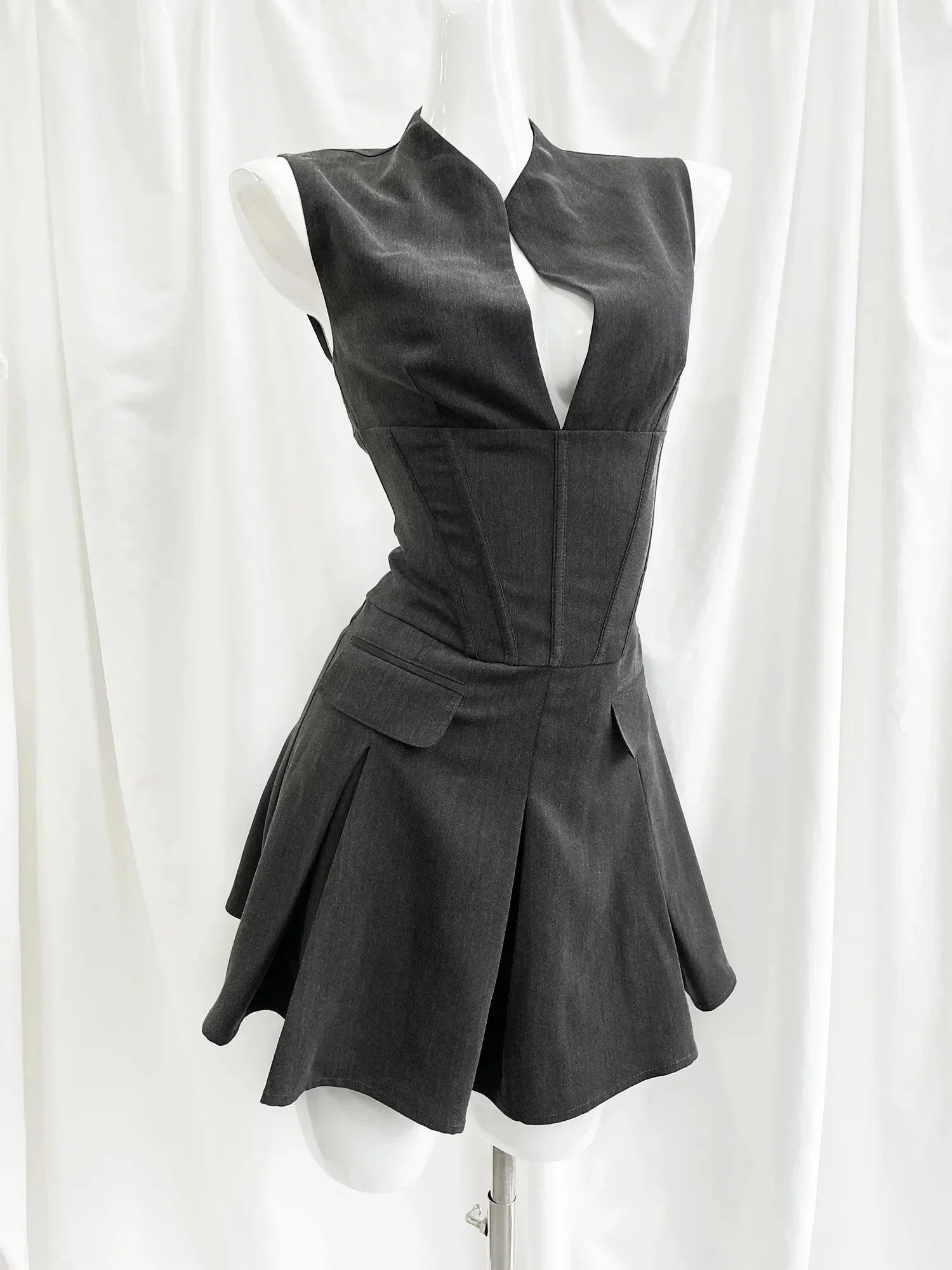 Black sleeveless dress on a mannequin against a white curtain background