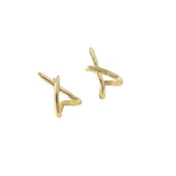 Gold earrings on a light beige surface with a white background