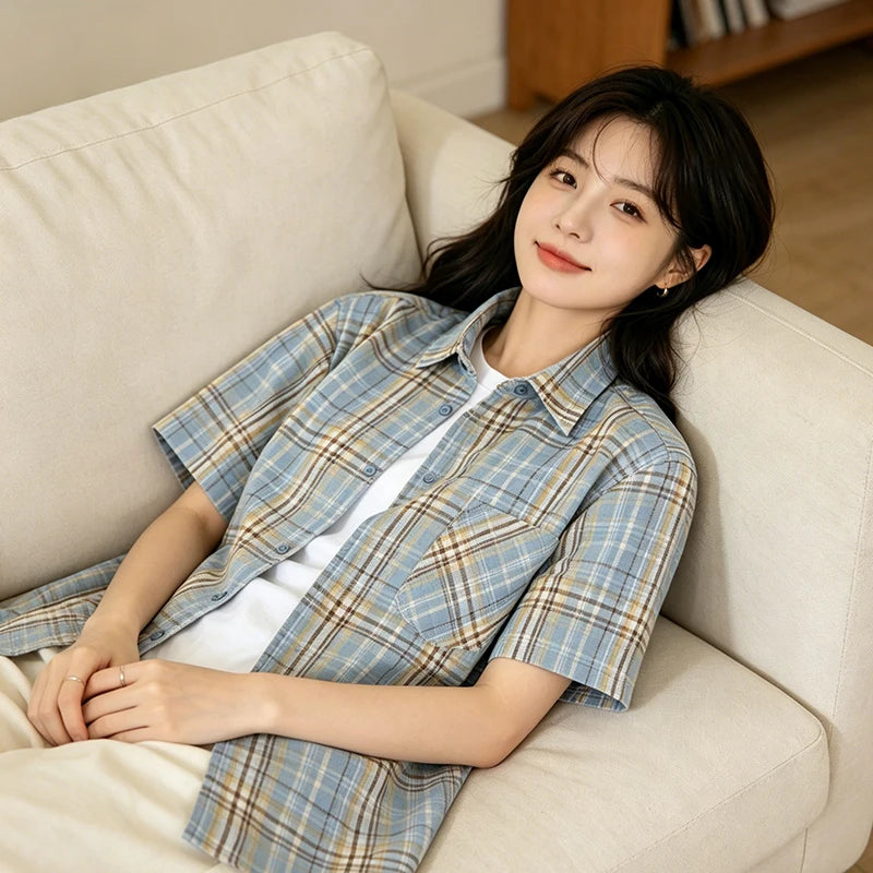 Woman wearing a blue plaid shirt sitting on a beige couch.