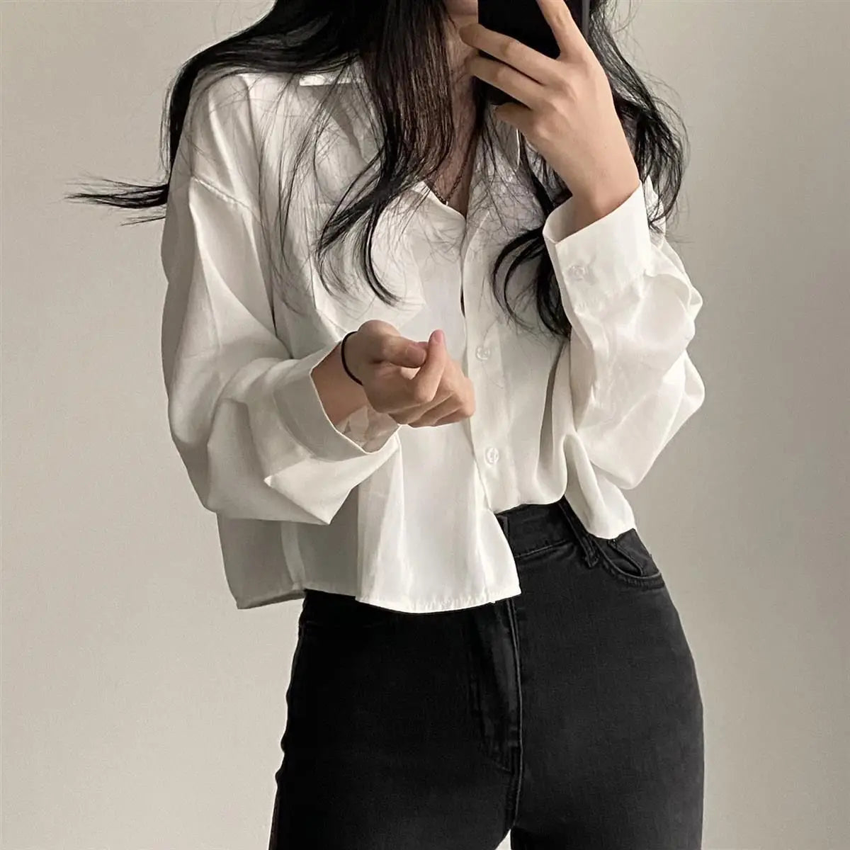 Person wearing a white blouse and black pants against a plain background