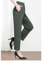 Person wearing green pants and black high heels on a white background
