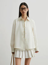 Woman wearing a cream-colored jacket and skirt on a plain background