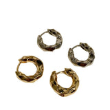 Four gold and silver hoop earrings on a light beige background
