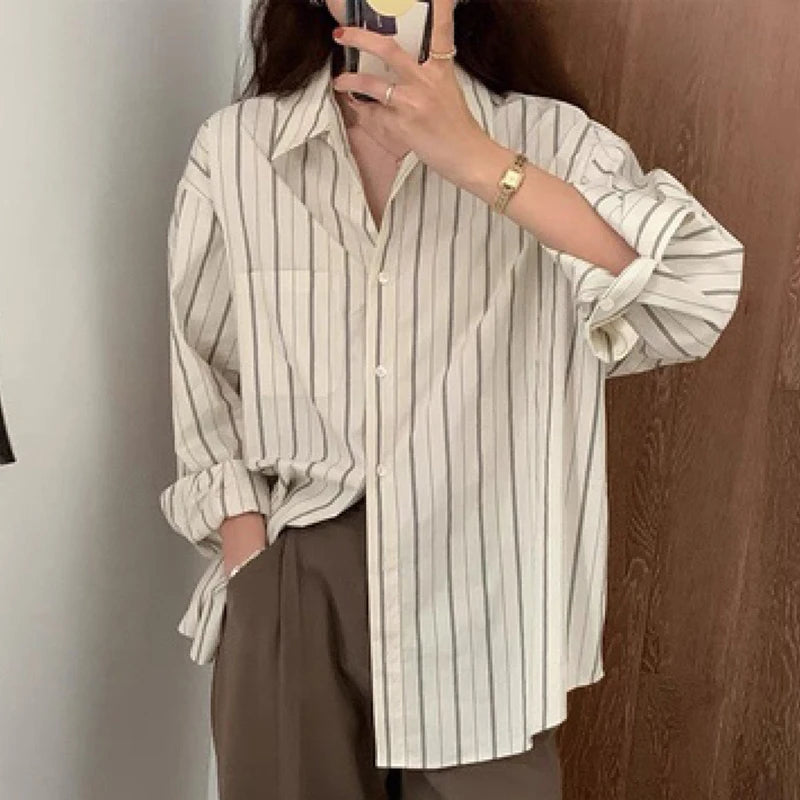 Person wearing a striped shirt and brown pants taking a mirror selfie.