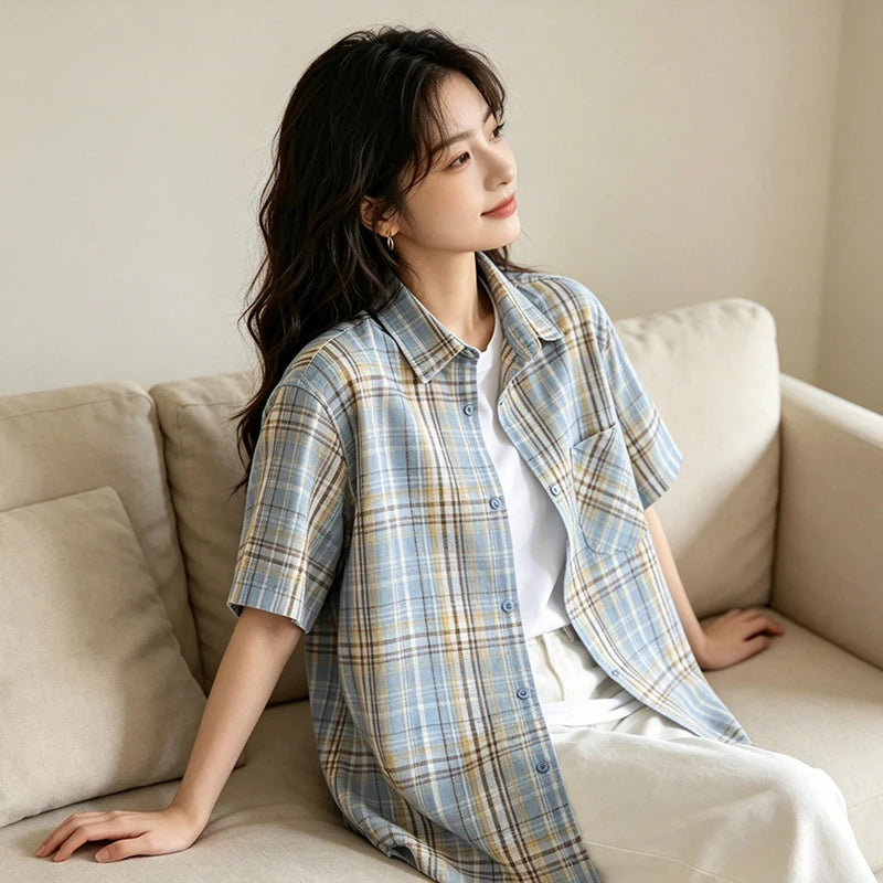 Woman sitting on a beige couch wearing a plaid shirt and white pants.