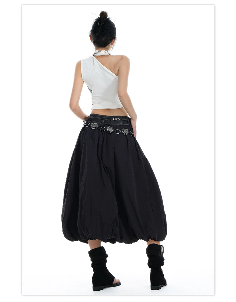 A woman shown from the back wearing a white one-shoulder top, a black harem-style skirt with a silver coin belt, and black slouchy ankle boots, against a plain white background.