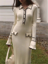 Woman wearing a long, cream-colored dress with black trim in an outdoor setting.