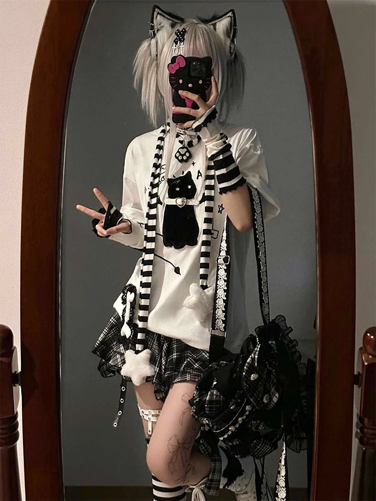 Person wearing a black and white outfit with cat-themed accessories in front of a mirror.