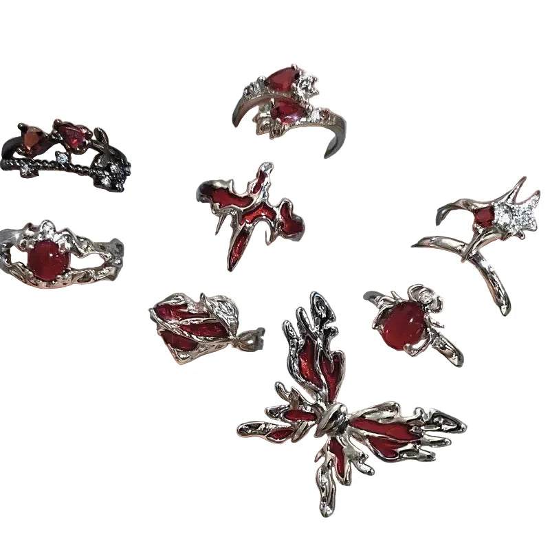 Multiple silver rings with red gemstones on a hand against a gray background