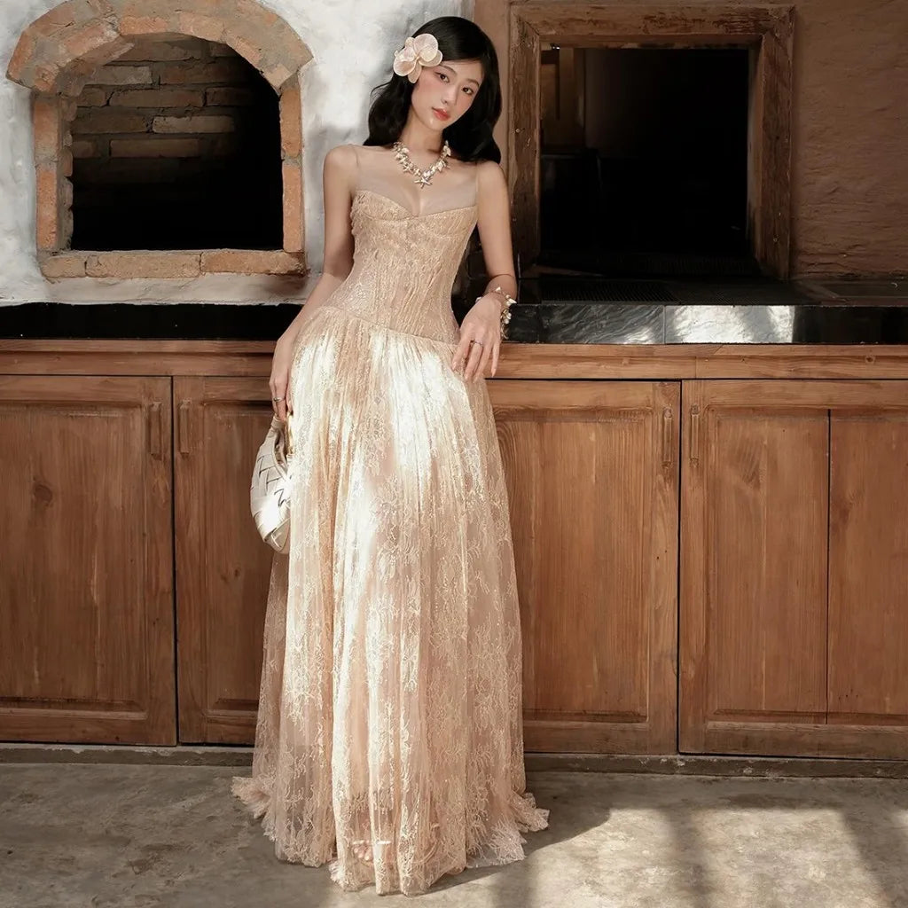 Woman in a beige lace dress standing in front of wooden cabinets.
