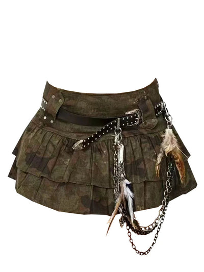 A stoked, punk-style mini skirt in olive green camouflage fabric, featuring pleated layers, a black studded belt, silver chain accents, and feathers, shown against a plain white background.