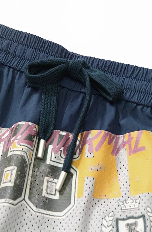 Close-up of navy blue athletic shorts with a dark green drawstring, featuring a graphic print with yellow, gray, and pink elements.