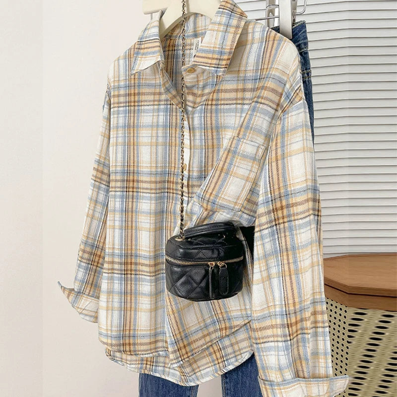 Plaid shirt with a black handbag on a hanger against a neutral background