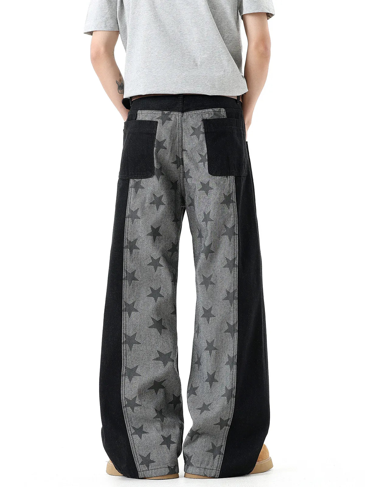 A person shown from the back wearing wide-leg pants with a gray and black star pattern and black side panels, paired with a light gray t-shirt against a white background.