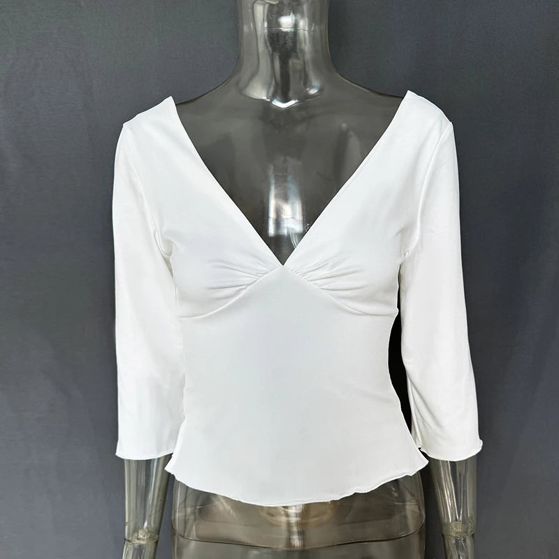 White blouse with a V-neck and three-quarter sleeves on a mannequin against a gray background