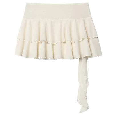 An off-white ruffled mini skirt with a wide waistband and a long side drape, shown against a plain white background.