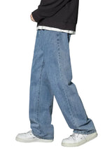 Person wearing blue jeans and white sneakers on a gray background
