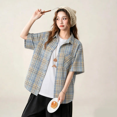 Woman wearing a plaid shirt over a white top, holding a plate with an egg and a straw hat on a plain background