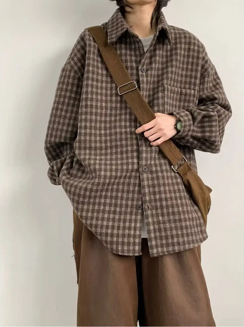 Person wearing a brown plaid shirt and brown pants with a brown bag over one shoulder against a white background.
