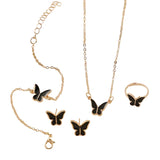 Butterfly-themed jewelry set including necklace, bracelet, earrings, and ring on a soft beige background.