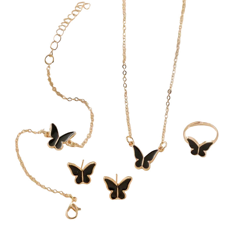 Butterfly-themed jewelry set including necklace, bracelet, earrings, and ring on a soft beige background.