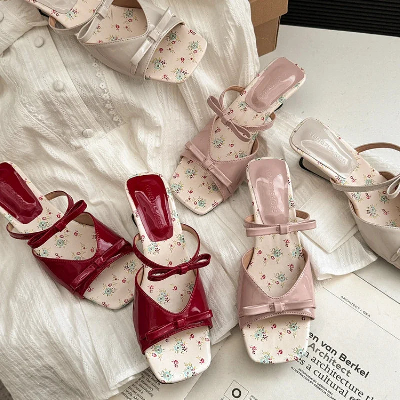Pair of red and pink floral shoes on a white fabric background
