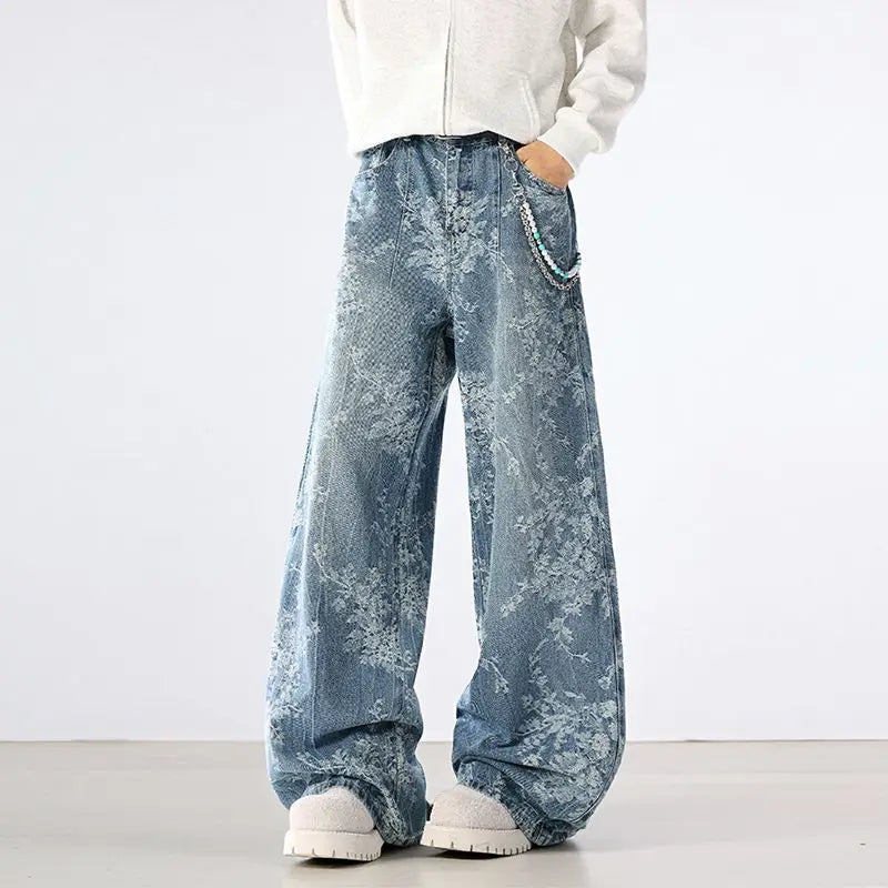 Person wearing wide-leg distressed jeans and white sneakers on a plain background