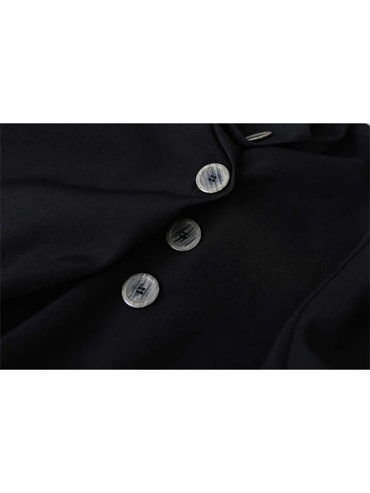 Close-up of a black button-up shirt showing three round silver buttons with a textured center, set against a plain white background.