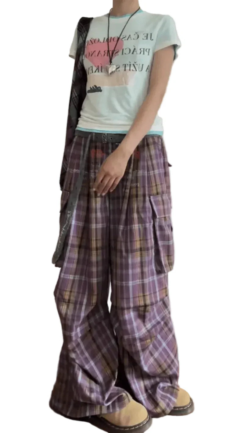 Person wearing a light-colored t-shirt and plaid pants with a plain background