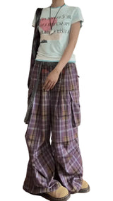 Person wearing a light-colored t-shirt and plaid pants with a plain background