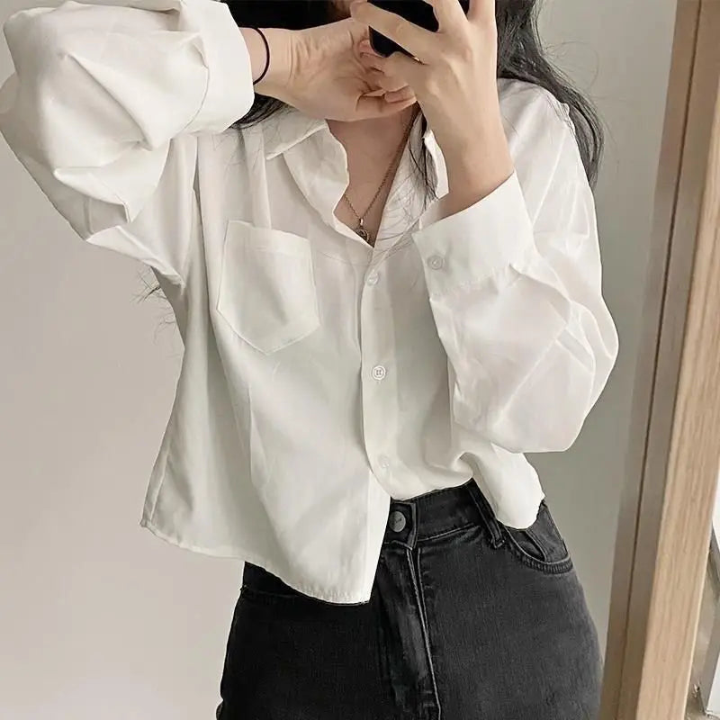 Person wearing a white blouse and black pants against a neutral background