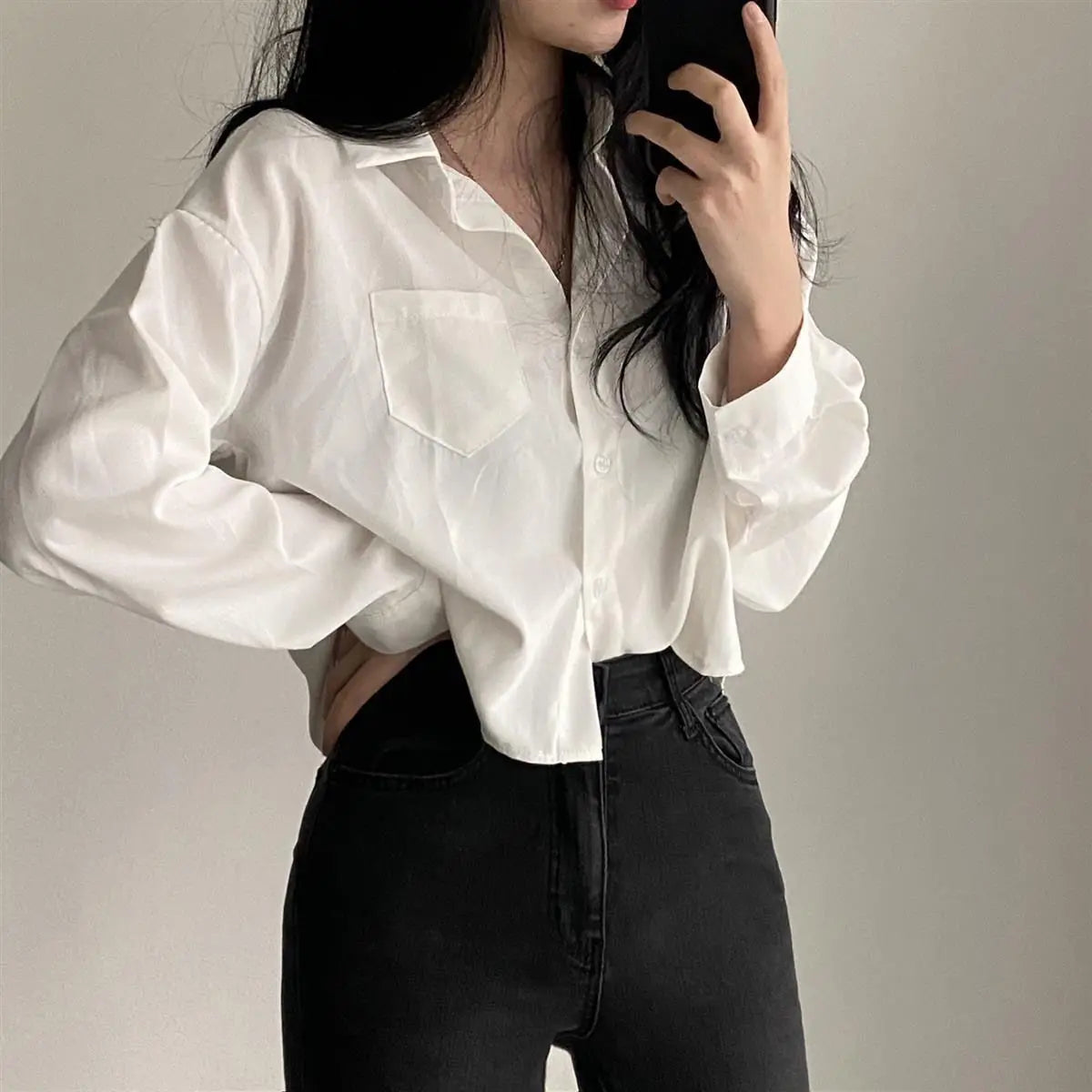 Person wearing a white blouse with puffed sleeves and black pants against a neutral background