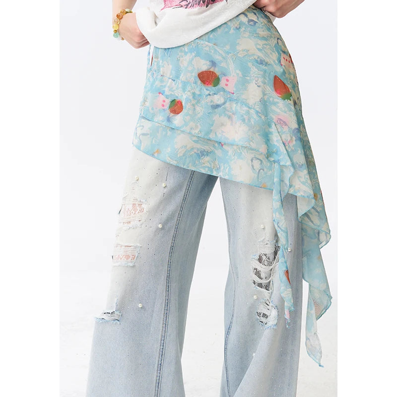 A person wearing a light blue floral wrap skirt or sash with strawberry motifs over distressed light-wash jeans, shown from the waist down against a plain white background.