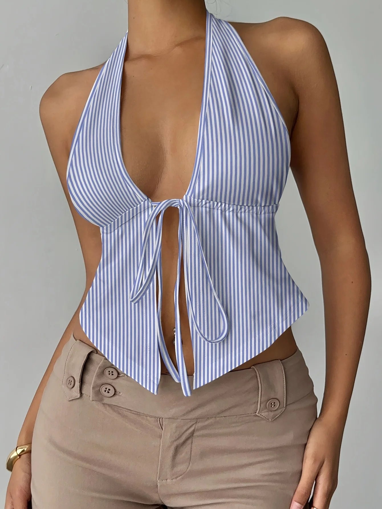 Blue and white striped halter top worn by a person on a gray background