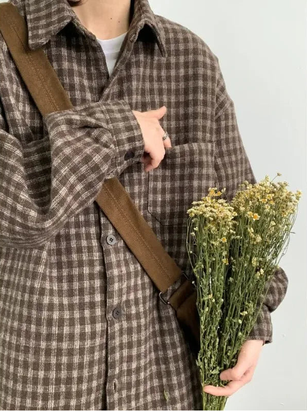 Person wearing a plaid coat holding a bouquet of flowers against a plain background