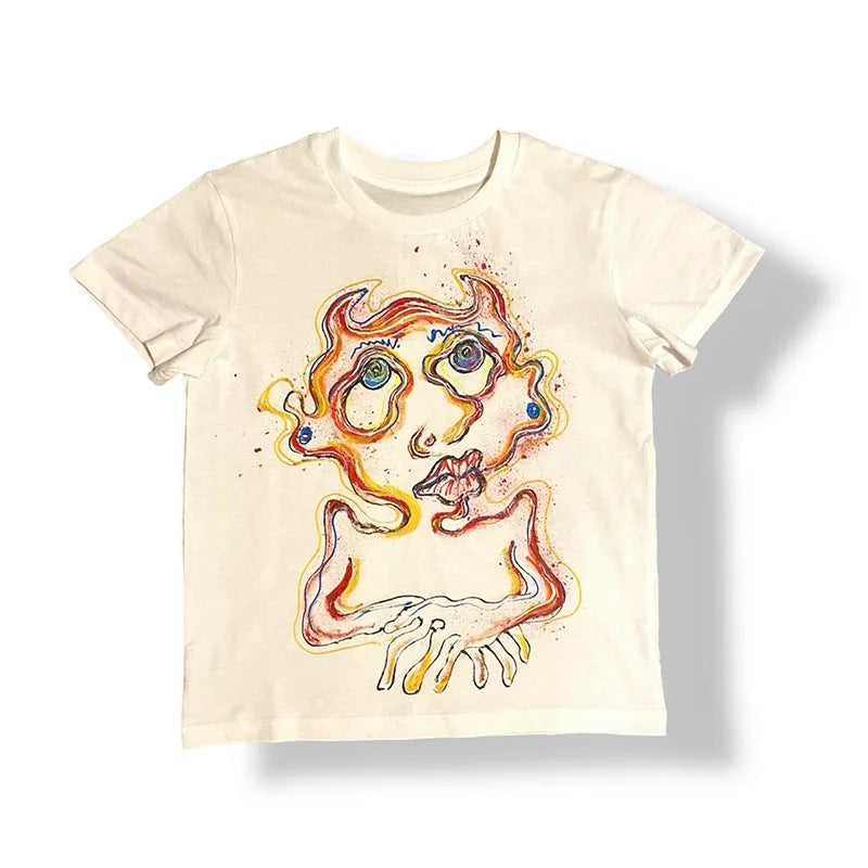 An off-white short-sleeve t-shirt featuring a surreal, colorful abstract face graphic in orange, yellow, and blue tones, displayed flat against a white background.