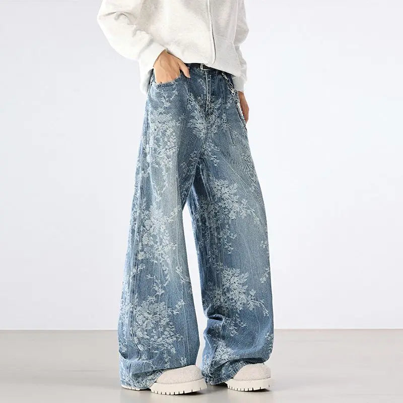 Person wearing blue floral-patterned jeans and a white sweatshirt on a plain background