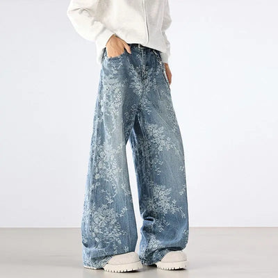 Person wearing blue floral-patterned jeans and a white sweatshirt on a plain background